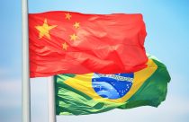 bandeira da china em primeiro plano com bandeira do brasil atras